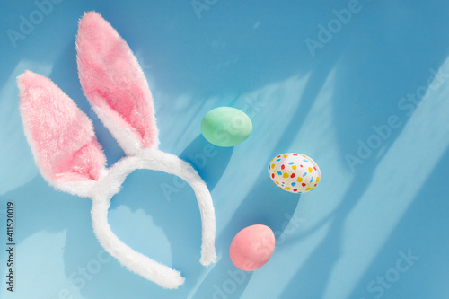 happy easter creative background bunny ears headband and colored eggs natural sun light effect flat lay 