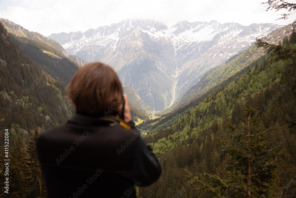 Man photographing beautiful mountainous landscape with valley and forests