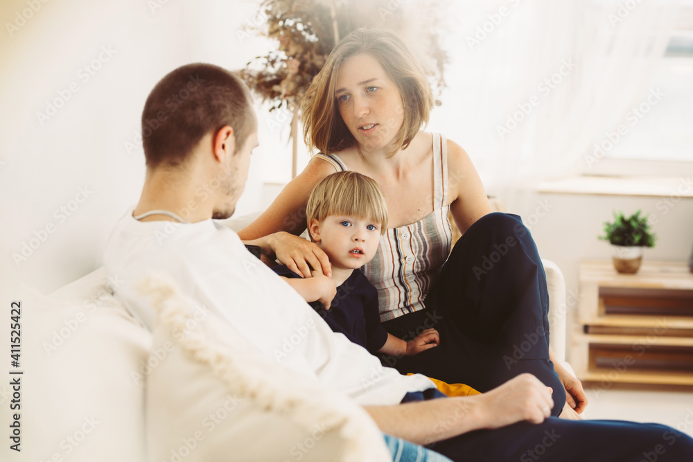 young family, mom, dad and little son are sitting on the sofa in the interior and chatting