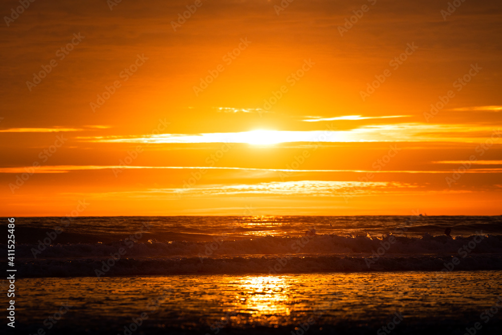 Silhouette scene of sea view during the wave is coming with dramatic orange sky and sun lighting background. Selective focus at the wave. High contrast.