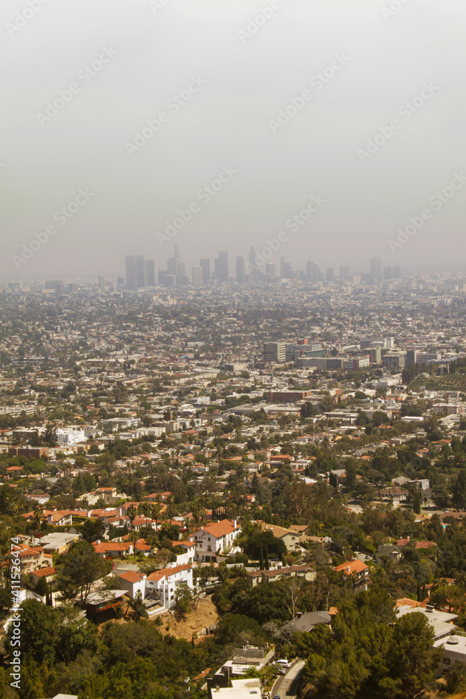 View over Los Angeles suburbs from Hollywood Hills with the city centre downtown blurred from fog in the distance.