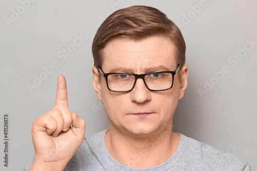 Portrait of serious focused mature man raising index finger