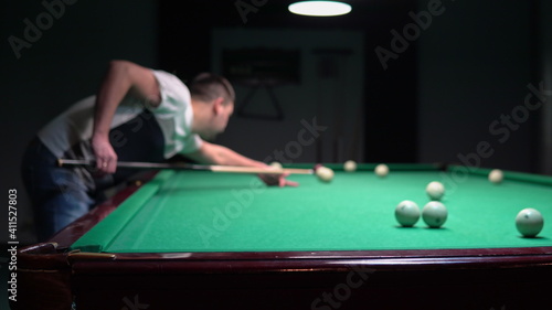 A man plays Russian billiards. aims with the cue and hits the ball