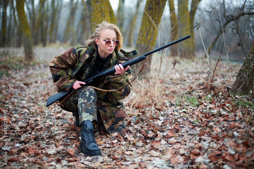 caucasian woman in camouflage suit and sunglasses with shotgun i
