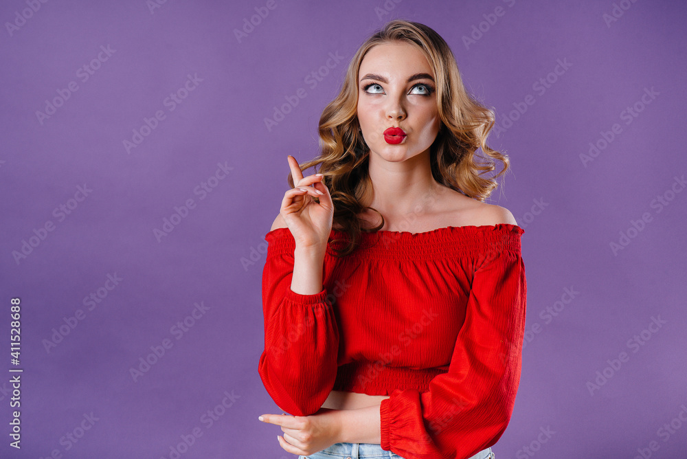 A young beautiful girl shows emotions and smiles in the Studio on a purple background. Girls for advertising A young beautiful girl shows emotions and smiles in the Studio on a purple background. Girls for advertising