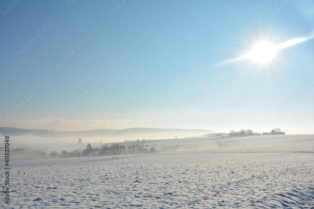 Snow landscape with fields and fog in the valley and with sun and  sky