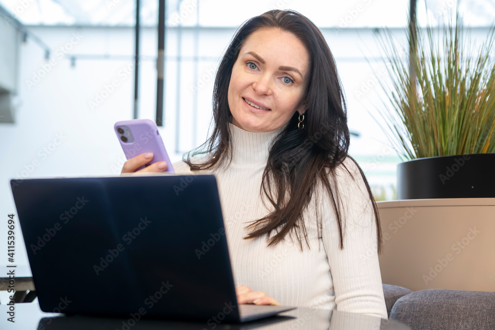 young woman works on laptop and smartphone in cafe. young woman works on laptop and smartphone in cafe.