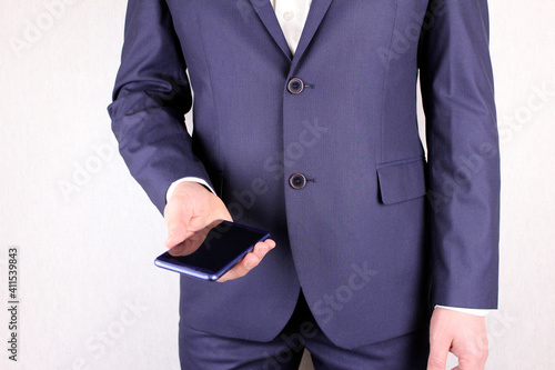 Businessman in a suit with a phone in his hand. Torso of a man in a blue suit with a smartphone