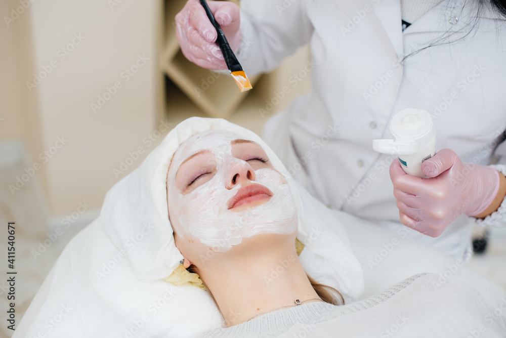 Naklejka premium A young girl in a cosmetology office is undergoing facial skin rejuvenation procedures. Cosmetology.