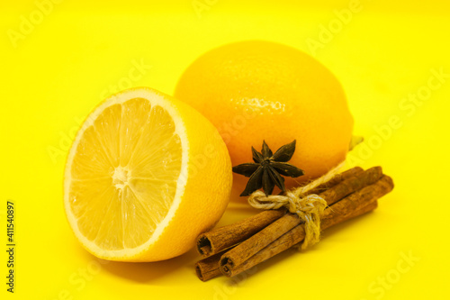 Sliced lemon and cinnamon sticks on yellow background