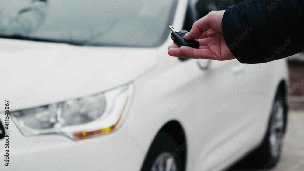 Driver unlocking the car by the car's key remote control with flashing car headlight Driver unlocking the car by the car's key remote control with flashing car headlight
