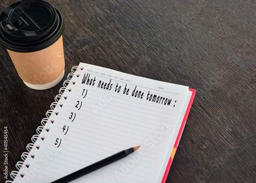 text on notepad with background of cup of coffee and a pen