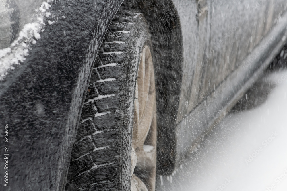 Nahaufnahme von einem Autoreifen,  vereister Reifenprofil in einem Schneesturm. Sicherheit im Winter nur mit Winterreifen.