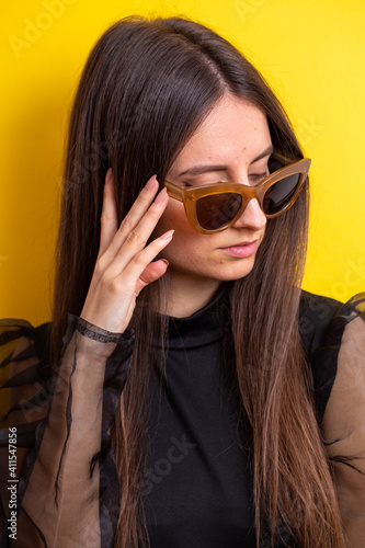 young woman with make-up in sunglasses and on yellow background
