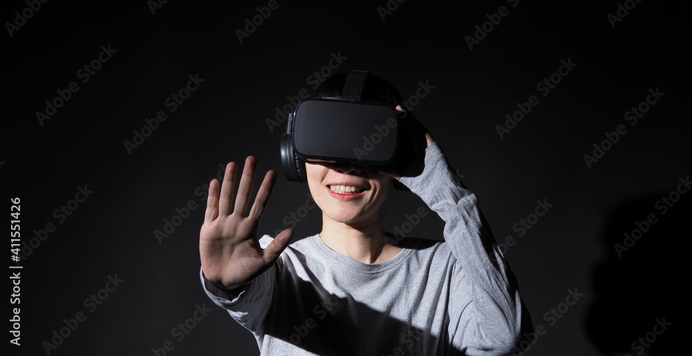 Girl with hands up wearing the VR headset goggles. Asian woman in glasses of virtual reality. The concept of futuristic. Digital VR glasses. Woman getting cyber experience using modern black color VR. Girl with hands up wearing the VR headset goggles. Asian woman in glasses of virtual reality. The concept of futuristic. Digital VR glasses. Woman getting cyber experience using modern black color VR.