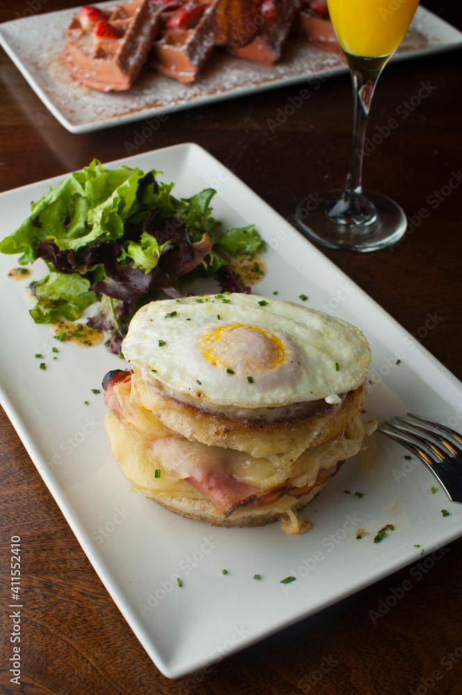 Croque madame or monsieur. Breakfast or brunch favorite: toast, with fried eggs, ham, cheese, and hollandaise sauce. Served with potato hash. Classic French bistro or American restaurant entree. Croque madame or monsieur. Breakfast or brunch favorite: toast, with fried eggs, ham, cheese, and hollandaise sauce. Served with potato hash. Classic French bistro or American restaurant entree.