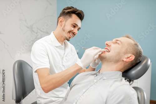 Cheerful dentist adjusting dental braces during orthodontic treatment for the young male patient. High quality photo