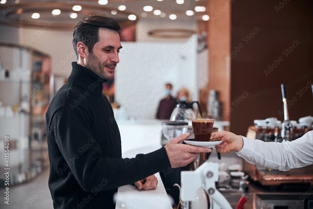 Happy man buying cup of hot drink in cafe Happy man buying cup of hot drink in cafe