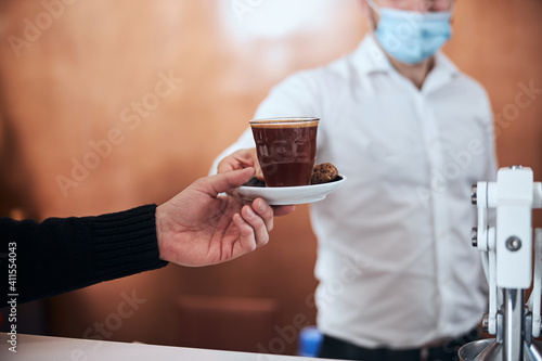 Waiter serving coffee to man during quarantine