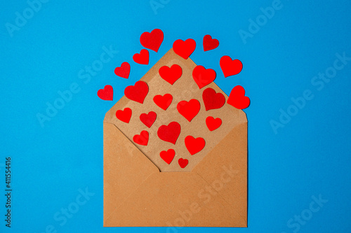 offener Briefumschlag aus dem rote papierherzen kommen auf blauem hintergrund high angle view