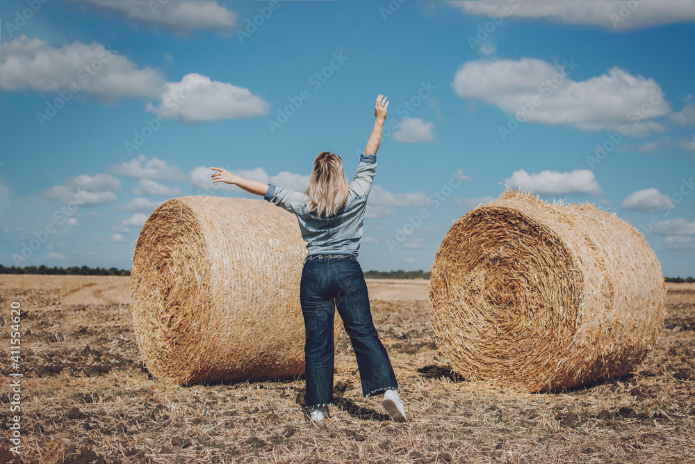 Body positive, high self esteem freedom, concept. Plus size Overweight woman celebrating rising hands to the sky and enjoys life on mowed wheat field with straw bales on sunny summer day Body positive, high self esteem freedom, concept. Plus size Overweight woman celebrating rising hands to the sky and enjoys life on mowed wheat field with straw bales on sunny summer day