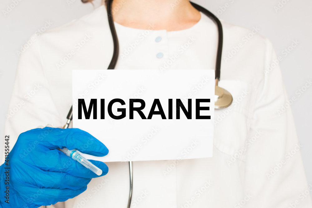 The doctor's blue - gloved hands show the word MIGRAINE - . a gloved hand on a white background. Medical concept. the medicine The doctor's blue - gloved hands show the word MIGRAINE - . a gloved hand on a white background. Medical concept. the medicine