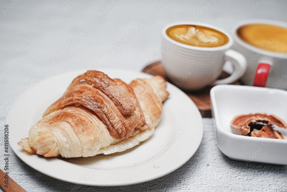 cup of coffee and Fresh baked croissant on white kitchen table. Top view with copyspace for your text. cup of coffee and Fresh baked croissant on white kitchen table. Top view with copyspace for your text.