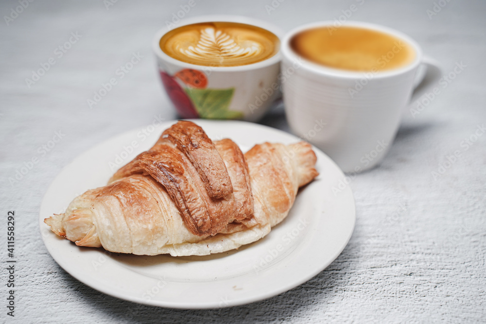 cup of coffee and Fresh baked croissant on white kitchen table. Top view with copyspace for your text. cup of coffee and Fresh baked croissant on white kitchen table. Top view with copyspace for your text.