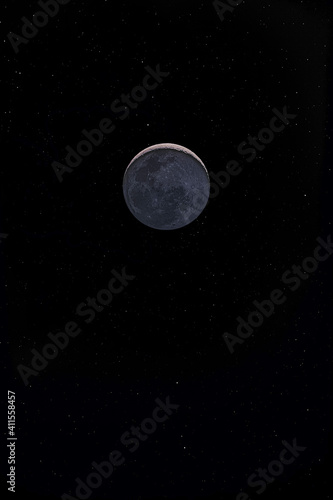Waxing crescent moon with a night sky stars background. Amazing view of the tiny moon surface illuminated by the sun and the dark side of the moon. Dramatical thin line cut out in the starry nighsky