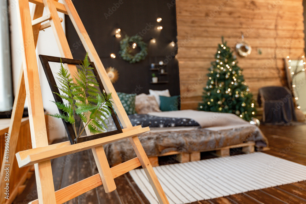 On the eve of the holiday, the interior of the country house is decorated with a New Year tree. large spacious light room decorated with wood with simple wood furniture