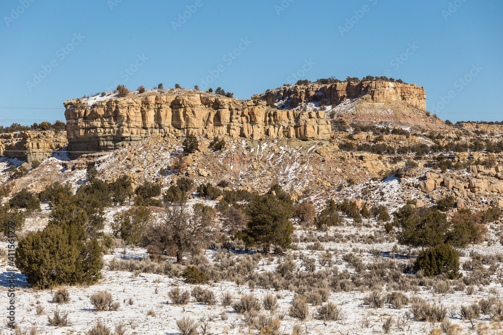 Beautiful rocky mountain formation with snow covered desert vista on clear day in rural New Mexico