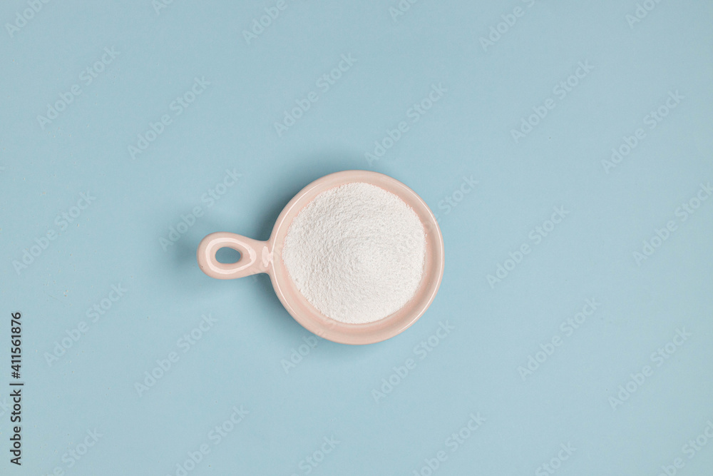 Collagen powder or protein in pink bowl on a blue background with copy space. Top view. Cosmetic skin care concept. Collagen powder or protein in pink bowl on a blue background with copy space. Top view. Cosmetic skin care concept.