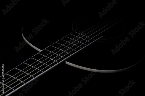 low-key photo of a fragment of a black guitar against a dark background. guitar music photo aesthetic