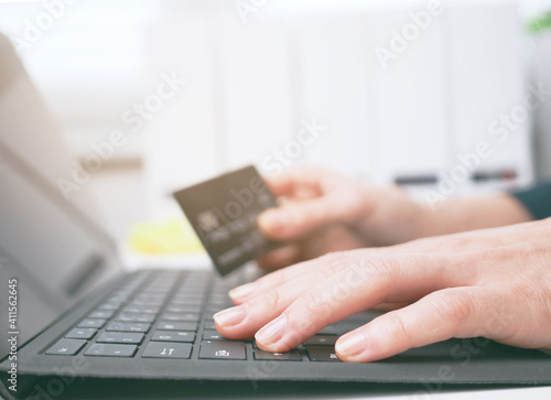 young woman holding credit card and using laptop and smartphone. Online shopping, booking and banking concept. Businesswoman or entrepreneur in the home office.