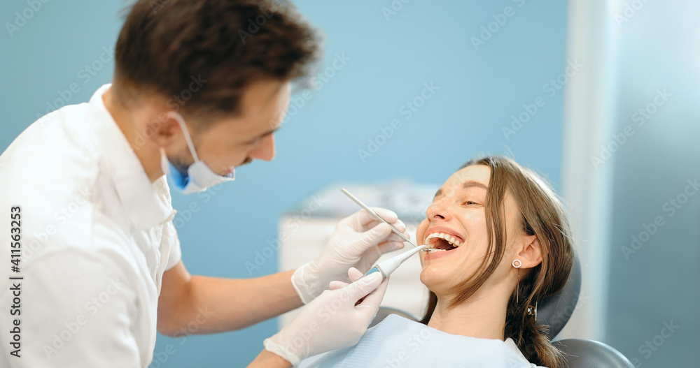 Fototapeta premium Young patient during a dental checkup. Dentist examining teeth of a woman at the dental office. 4k video screenshot, please use in small size