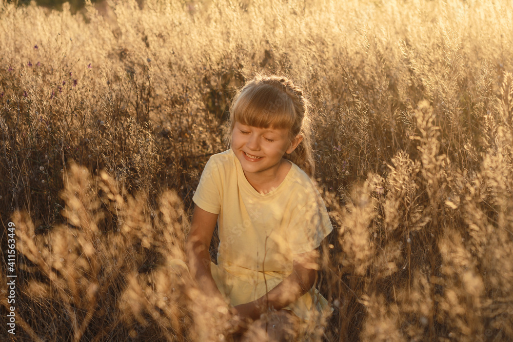 Little beautiful happy girl in a field bathed in sun at sunset. Little beautiful happy girl in a field bathed in sun at sunset.