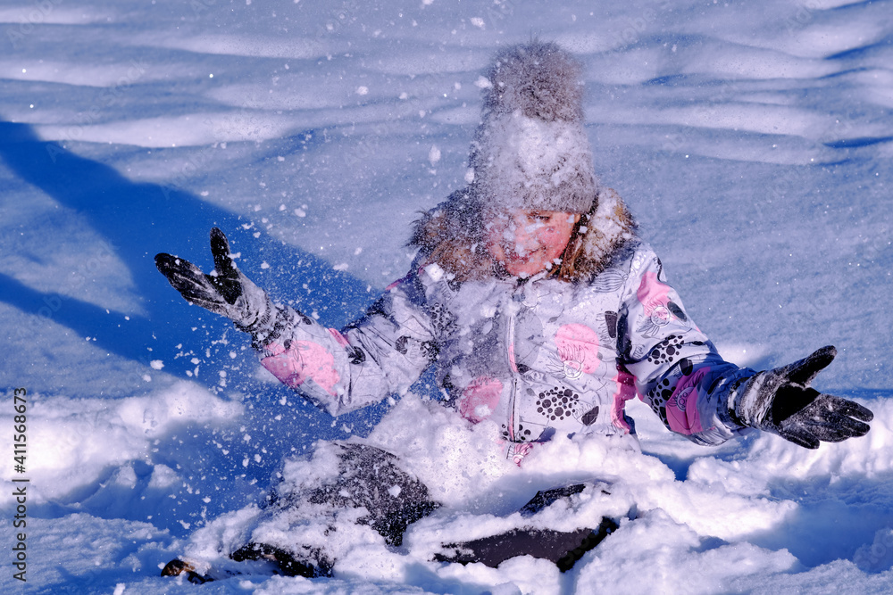 Obraz premium The girl plays with snow. Child rejoices in winter. Happy childhood.