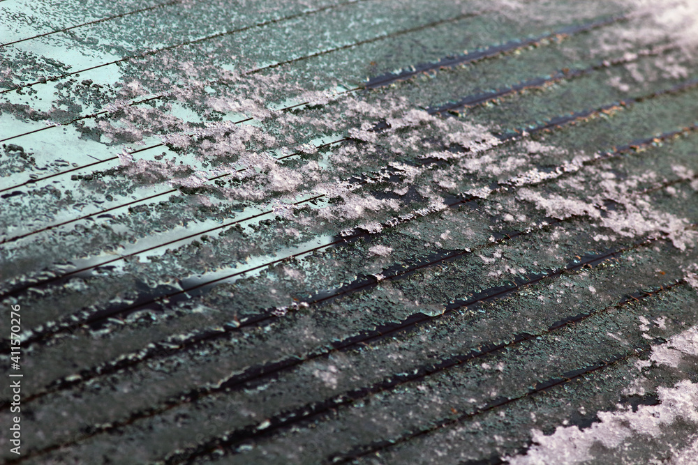 Melting ice on the rear window of the car. Close-up view of