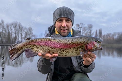 Fototapeta Naklejka Na Ścianę i Meble -  Rainbow trout fishing. Fisherman with motley salmon fish at area pond