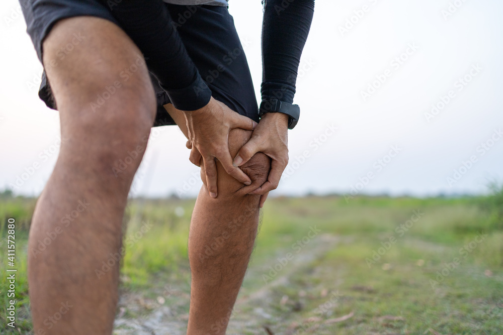 sporty man suffering with knee pain while exercising outdoors sporty man suffering with knee pain while exercising outdoors