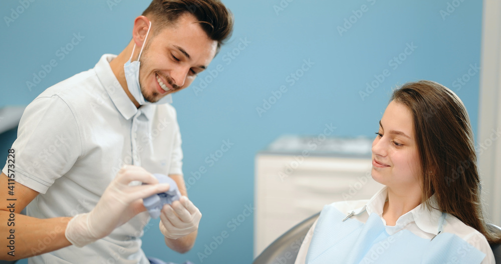 Dentist showing a jaw model, explaining to the young patient the process of orthodontic treatment. Girl with dental braces with a dentist. 4k video screenshot, please use in small size Dentist showing a jaw model, explaining to the young patient the process of orthodontic treatment. Girl with dental braces with a dentist. 4k video screenshot, please use in small size