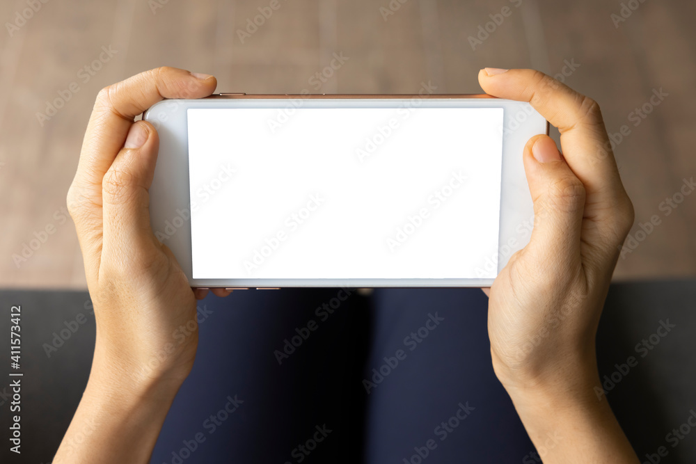 Close-up woman of hand held with smart phone white screen on sofa in the living room. Concept of technology, connection, communication. Close-up woman of hand held with smart phone white screen on sofa in the living room. Concept of technology, connection, communication.