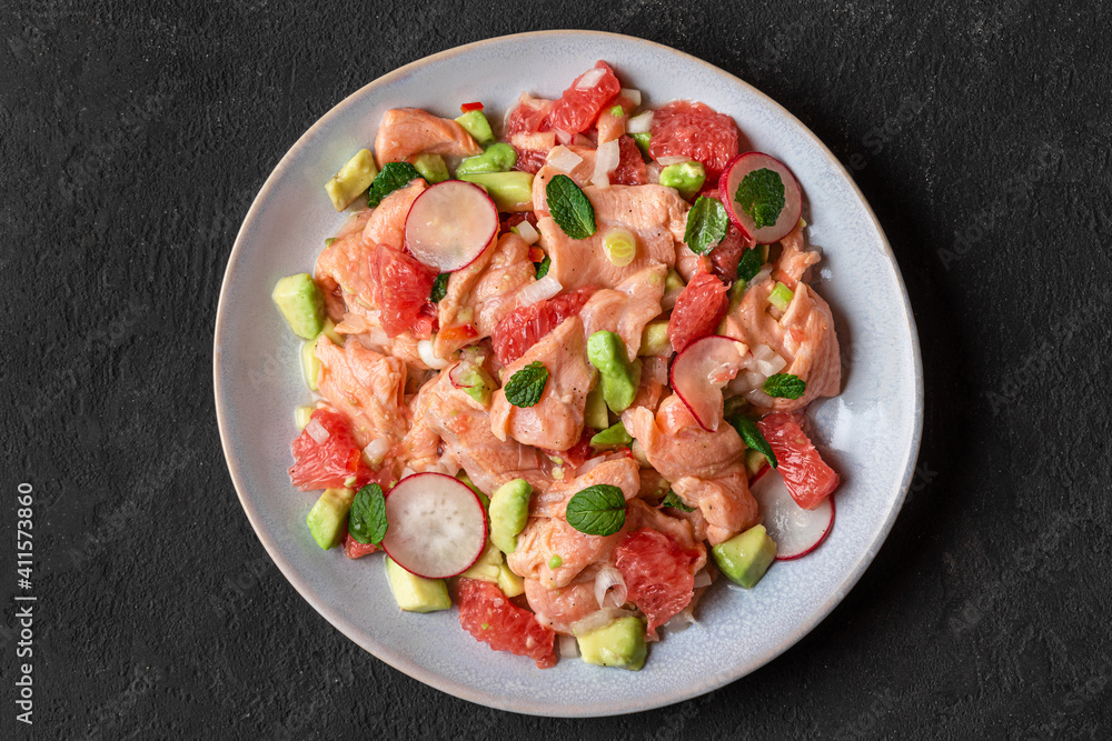 Salmon ceviche with grapefruit, avocado, radish, onion and mint in a plate on dark background. Healthy diet food. top view Salmon ceviche with grapefruit, avocado, radish, onion and mint in a plate on dark background. Healthy diet food. top view