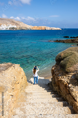 Young woman taking photos of Karavostasi Bay on the east coast of Folegandros Island.