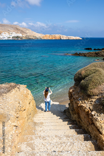 Young woman taking photos of Karavostasi Bay on the east coast of Folegandros Island. photo