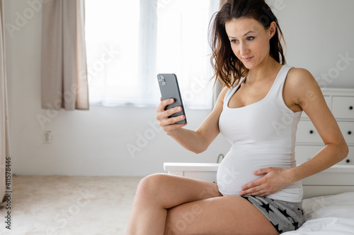 Pregnant woman holds hand on belly. Pregnancy, maternity, preparation and expectation concept. Close-up, copy space, indoors. Beautiful tender mood photo of pregnancy.
