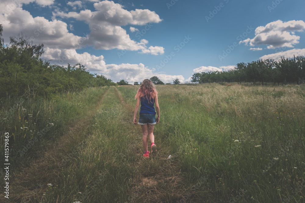 Naklejka premium child in green nature walking along back view