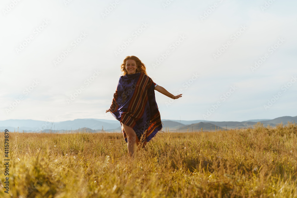 A girl with a shawl on her shoulder runs on the steppe with yellowed grass spreading her arms to the sides. High quality photo A girl with a shawl on her shoulder runs on the steppe with yellowed grass spreading her arms to the sides. High quality photo