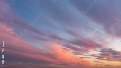 Dramatic vanilla skyscape. Purple orange sunset clouds against blue sky. Scenic dynamic low clouds in a twilight heaven. Weather forecast, meteorology.