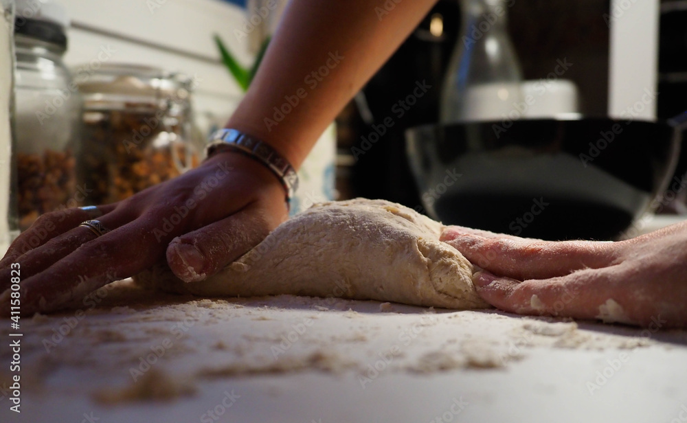 hands of a young woman with a bread dough in a white table
